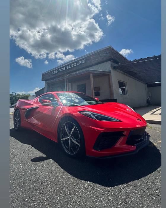 Red Corvette under a dramatic sky at the shop